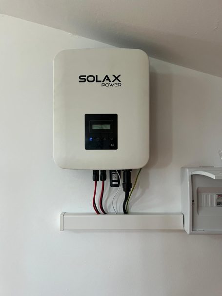 Solax Powe Inversor solar de la marca Solax montado en la pared, con conexiones visibles.