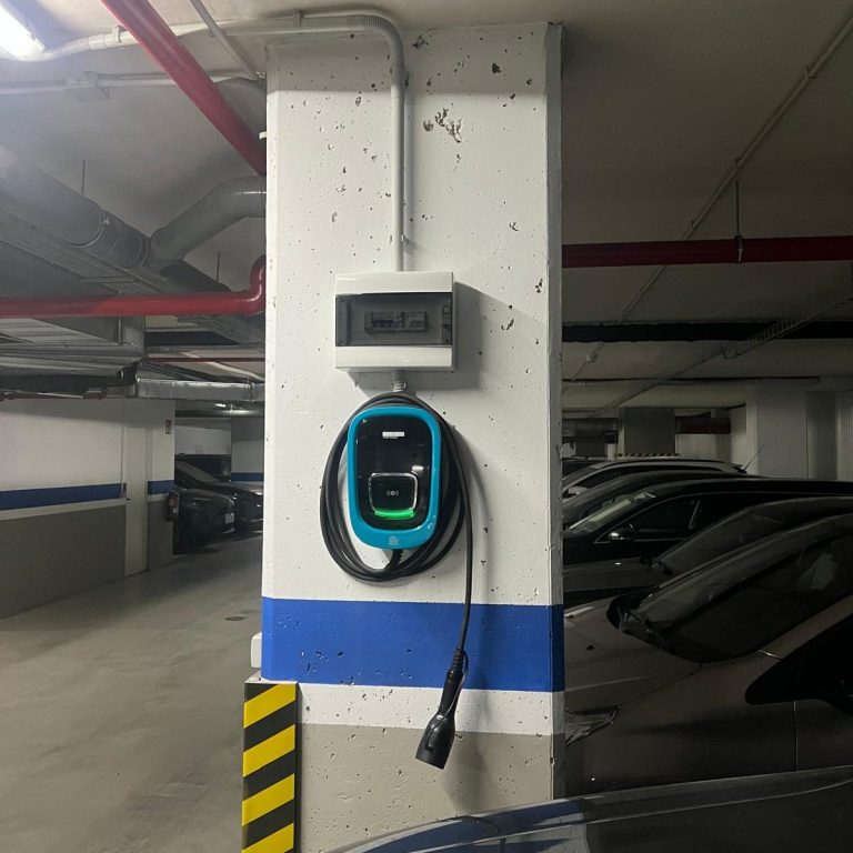 Cargador de coche Orbis Punto de carga para vehículos eléctricos en un aparcamiento subterráneo.